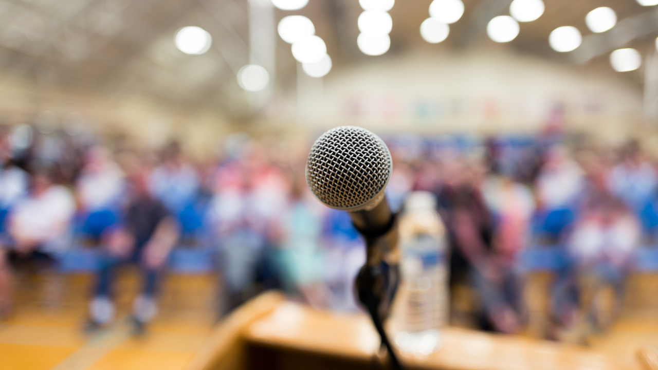 A microphone and podium at the front of a town hall meeting.